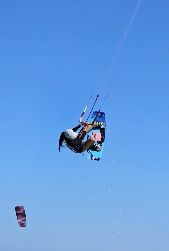 Kitesurfing jump against a clear blue sky
